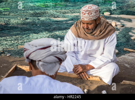 Muscat, Oman - 4. Februar 2017: Zwei gekleidet traditionell omanischen Männer spielen ein traditionelles Spiel. Stockfoto