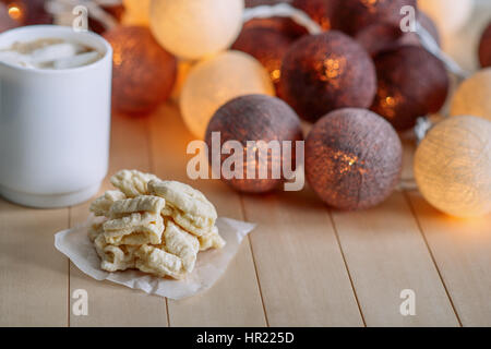 Stapeln Sie nach Hause Mama Cookies auf hölzernen natürlichen Hintergrund. In der Nähe der Cookie ist weiße Tasse mit Kaffee und weiße Marshmallows. Im Hintergrund Leuchten runden h Stockfoto