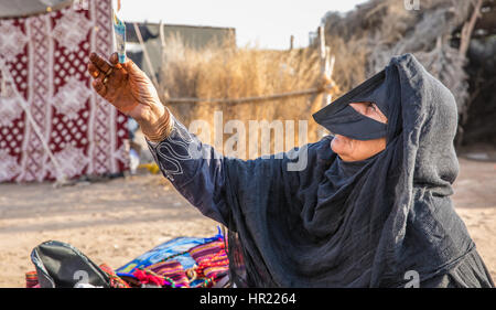 Muscat, Oman - 4. Februar 2017: Eine alte omanische Frau gekleidet in eine traditionelle Kleidung, die ihre waren auf einem Markt zu zeigen. Stockfoto