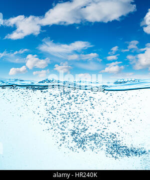Viele Luftblasen im Wasser ganz nah, abstrakte Wasserwelle mit Luftblasen auf einem Hintergrund des blauen Himmels Stockfoto