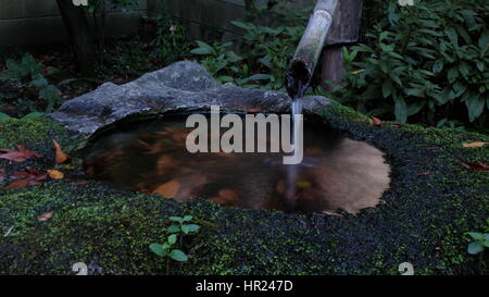 Orientalischer Bambus Brunnen mit Wasser fließt in einen kleinen Felsen Teich, Japan Stockfoto