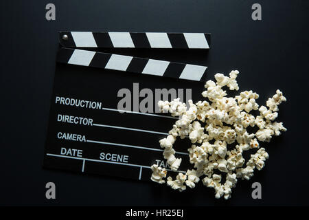 Klappe und Popcorn auf schwarzem Hintergrund. Ansicht von oben. Stockfoto