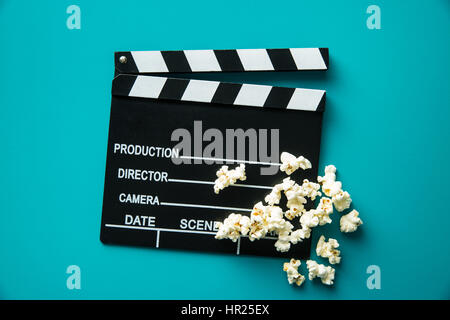 Klappe und Popcorn auf blauem Hintergrund. Ansicht von oben. Stockfoto
