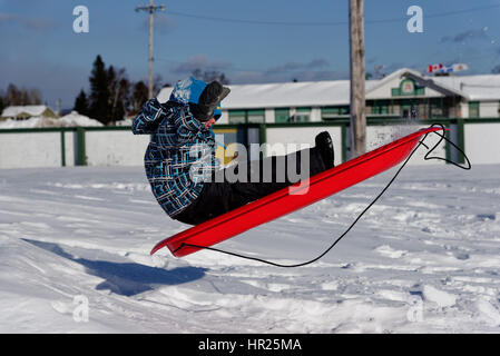 Ein kleiner Junge (4 Jahre alt) in die Luft sprang auf einem Schlitten in Quebec winter Stockfoto
