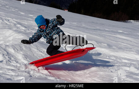 Ein kleiner Junge (4 Jahre alt) in die Luft sprang auf einem Schlitten in Quebec winter Stockfoto