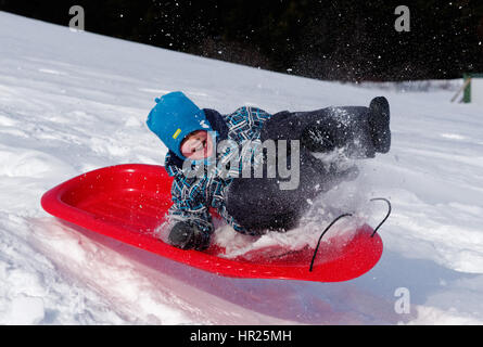 Ein kleiner Junge (4 Jahre alt) in die Luft sprang auf einem Schlitten in Quebec winter Stockfoto