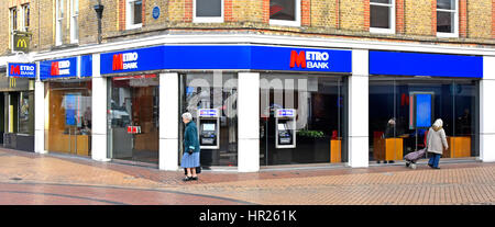 Metro-Bank Filiale Zeichen und Logos auf einer Ecke Website High Street Chelmsford Essex England UK Geldautomaten Bargeld darauf Automaten in Glas-Storefront Stockfoto