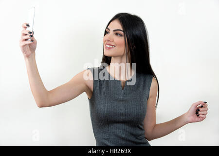 Junge Geschäftsfrau mit ihrem Smartphone eine Selfie schießen und lächelnd. Stockfoto