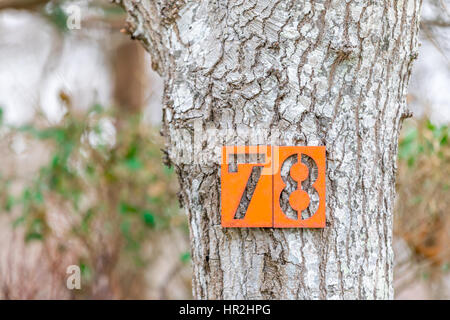 Hausnummer, an einem Baum auf der Seite einer Straße 78 Stockfoto