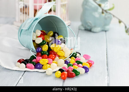 Eine blaue Blecheimer umgekippt, verschütten Gummibärchen auf den Tisch. Geringe Schärfentiefe. Stockfoto