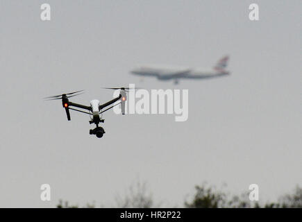 Eine Drohne fliegt im Hanworth Park in West London, als British Airways 747 Flugzeug zu landen am Flughafen Heathrow hinter bereitet. Stockfoto