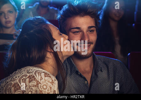 Romantisches Liebespaar im Kino, ist eine Mädchen ihren Freund auf die Wange küssen. Stockfoto