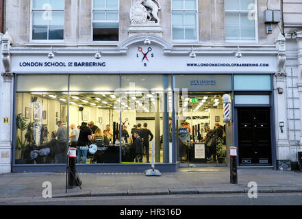 Außenansicht Innenraum London Schule der Barbering Shop mit Lehrling britischen Friseure Haare schneiden von Klienten in Smithfield, London UK KATHY DEWITT Stockfoto