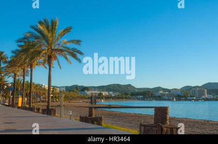 Späten Nachmittag Sonne fällt auf Strand, Marina & Promenade.  St. Antoni de Portmany, Ibiza, Spanien.  Leeren Strand & ruhigem Wasser gegen Abend Ansätze. Stockfoto