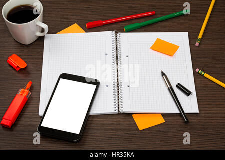Geöffnet Notebook, Smartphone mit leerer Bildschirm, Stift, Haftnotiz, Tasse Kaffee in Chaos auf dunklen Büro Schreibtisch aus Holz. Stockfoto