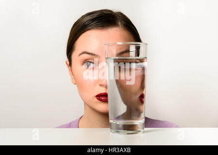 Frau Gesicht Verzerrungen im Glas Wasser Stockfoto