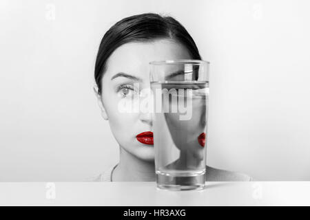 Frau Gesicht Verzerrungen im Glas Wasser Stockfoto