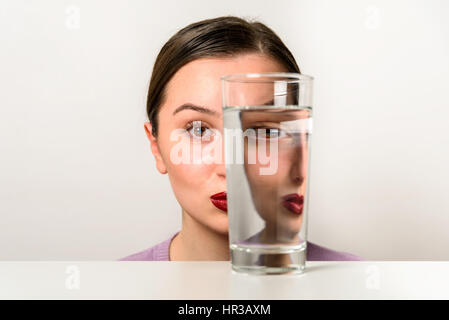 Frau Gesicht Verzerrungen im Glas Wasser Stockfoto