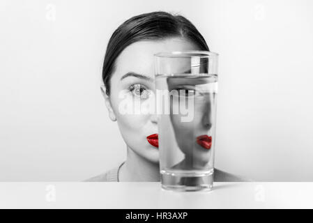 Frau Gesicht Verzerrungen im Glas Wasser Stockfoto