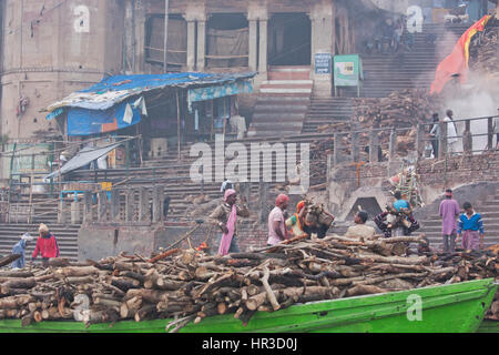 Arbeiter transportieren Holz für den Aufbau von Scheiterhaufen am Manikarnika Ghat, Varanasi am Ganges in den frühen Morgenstunden. Viele Feuerbestattungen finden hier statt Stockfoto