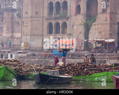 Arbeiter transportieren Holz für den Aufbau von Scheiterhaufen am Manikarnika Ghat, Varanasi am Ganges in den frühen Morgenstunden. Viele Feuerbestattungen finden hier statt Stockfoto