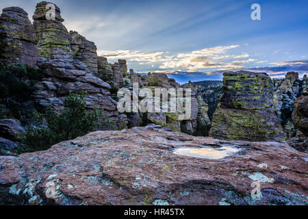 Die Sonne steigt über Chiricahua National Monument am Morgen nach einem Monsun-Sturm und der Himmel spiegelt sich in einem kleinen Pool. Stockfoto