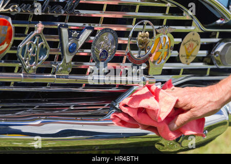 Oldtimer Vauxhall - Nahaufnahme von hochglanzpolierten Kühlergrill mit Vauxhall Logo und Kühlergrill Abzeichen. Zeigt Besitzer Hand Polieren Frontstoßstange. Stockfoto