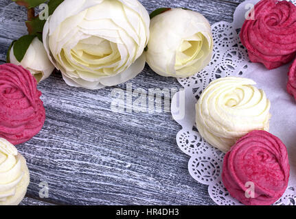 Weißer Hahnenfuß Blumen Ranunkeln weiß und rosa Zephyr Marshmallows lacy Papierserviette auf grauem Hintergrund aus Holz. Textfreiraum. Stockfoto