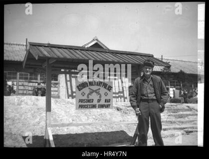 Amerikanischer Soldat stehend auf Vorderseite des Zeichens für die 8210th Militärpolizei Kriegsgefangener Processing Company im Jahr 1950 während des Koreakrieges. Stockfoto