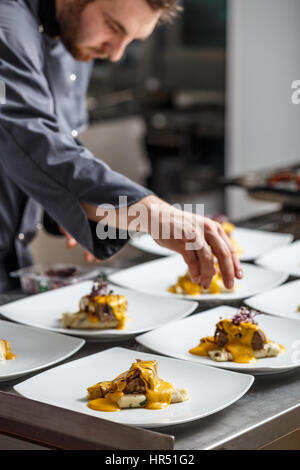 Junger Koch bereitet köstliche Mahlzeiten im Restaurantküche Stockfoto