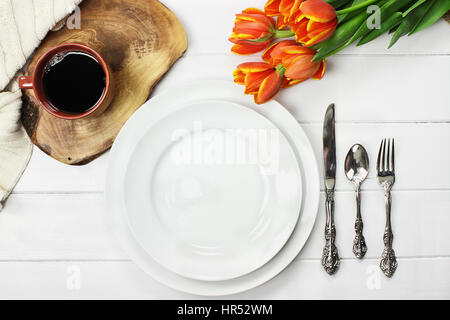 Overhead Schuss einen leeren Teller mit Kaffee und einen Strauß Tulpen Frühling über einen weißen Holztisch Top. Flache Laien Draufsicht Stil. Stockfoto