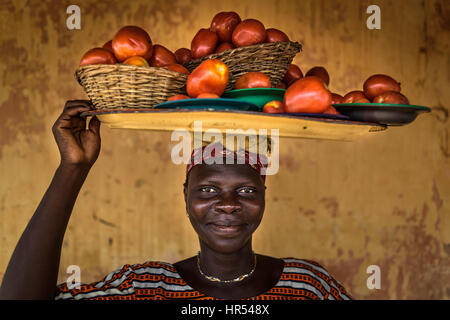 Afrikanische Frau mit einem Tablett von Tomaten auf den Kopf. Stockfoto