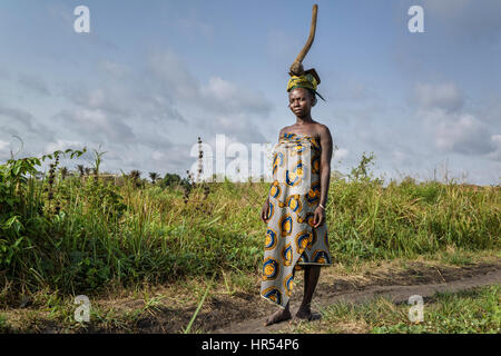 Porträt einer Frau vom Stamm Holi mit einer Hacke auf den Kopf. Sie kommt zurück von der Arbeit in den Bereichen. Frauen in Afrika werden verwendet, um e tragen Stockfoto