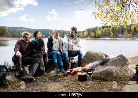 Voller Länge der happy multiethnischen Friends camping am Seeufer Stockfoto