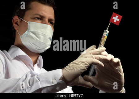 Junger Mann als Arzt gibt eine medizinische Einspritzung Schweizer Flagge auf einem schwarzen Hintergrund Stockfoto