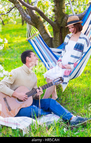 Schwangere paar im blühenden Garten beim Picknick. Zeit zum Faulenzen Stockfoto