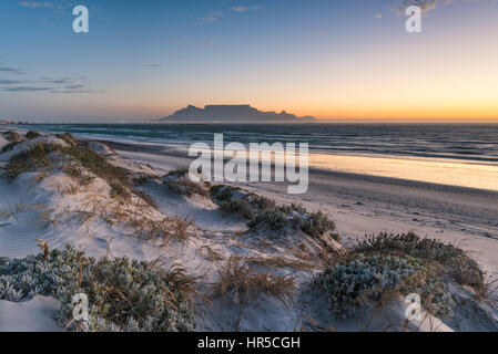 Blick auf den Tafelberg bei Sonnenuntergang von Big Bay Bloubergstrand, Kapstadt, Südafrika Stockfoto