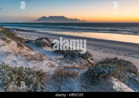 Blick auf den Tafelberg bei Sonnenuntergang von Big Bay Bloubergstrand, Kapstadt, Südafrika Stockfoto