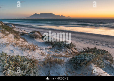 Blick auf den Tafelberg bei Sonnenuntergang von Big Bay Bloubergstrand, Kapstadt, Südafrika Stockfoto