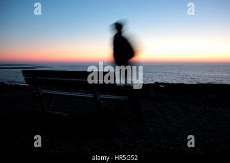 Mann läuft entlang der Küste am frühen Morgen Stockfoto