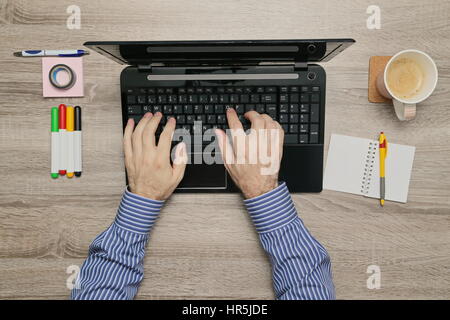 Männliche hand arbeiten am Laptop in seinem Büro während wie er Kaffee trinkt Stockfoto