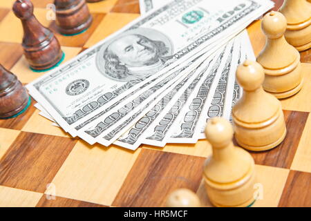 US-Dollar und Schach Figuren auf einem alten hölzernen Schachbrett Stockfoto