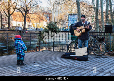 Berlin, Kreuzberg. Junges Kind beobachten Straßenmusiker Gitarre spielen und singen neben den Landwehrkanal Stockfoto