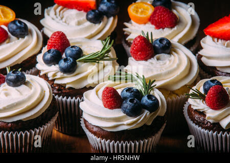 Frische leckere Schokolade Cupcakes mit Beeren. Selektiven Fokus. Dunklem Holz. Rustikaler Stil, Platz für Text. Stockfoto