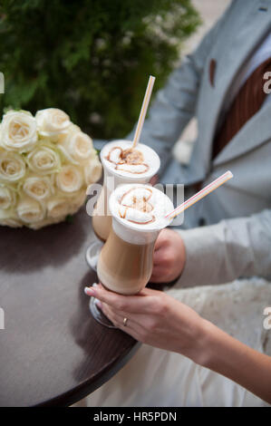 Braut und Bräutigam trinken Latte mit gemalten Herzen. Stockfoto