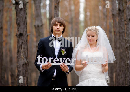 Braut und Bräutigam halten Holzbuchstaben lieben für immer. Stockfoto