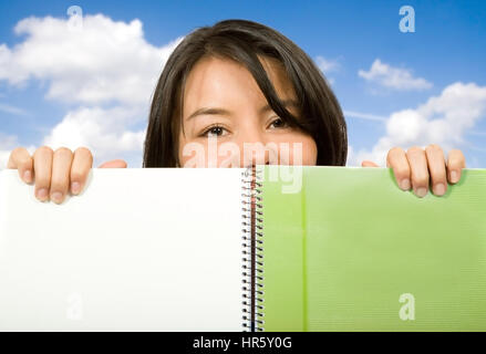 hübsche Studentin sucht über Notebook mit dem Himmel im Hintergrund Stockfoto