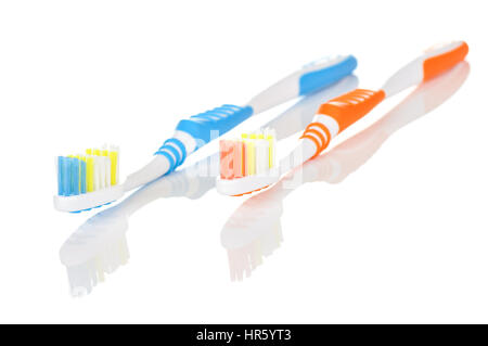 Paar von orangenen und blauen Zahnbürsten auf weißem Hintergrund mit Reflexion Stockfoto