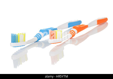 Paar von orangenen und blauen Zahnbürsten auf weißem Hintergrund mit Reflexion Stockfoto
