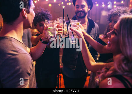 Gruppe junger Freunde im Club Toasten mit Cocktails. Junge Männer und Frauen im Nachtclub mit Getränken zu feiern. Stockfoto